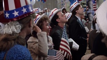 Movie still from “Bob Roberts” (1992), directed by Tim Robbins – A group of people wearing patriotic hats and holding american flags; Medium shot, High angle