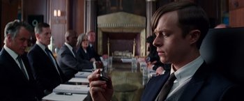 Movie still from “The Amazing Spider-Man 2” (2014), directed by Marc Webb – A man holding a cell phone in front of a group of people; Close Up shot, Over the shoulder angle