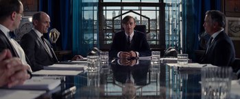 Movie still from “The Amazing Spider-Man 2” (2014), directed by Marc Webb – A man sitting at a table in front of a large window; Medium shot, Over the shoulder angle