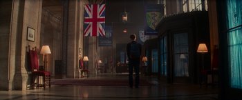 Movie still from “The Amazing Spider-Man 2” (2014), directed by Marc Webb – A person standing in a room with a flag hanging from the ceiling; Wide shot, Low angle