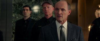 Movie still from “The Amazing Spider-Man 2” (2014), directed by Marc Webb – A man in a suit standing next to two other men; Close Up shot, Over the shoulder angle