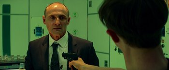 Movie still from “The Amazing Spider-Man 2” (2014), directed by Marc Webb – A man in a suit and tie holding a gun in front of a mirror; Close Up shot, Over the shoulder angle