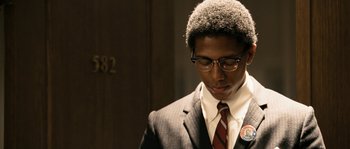 A man in a suit and tie standing in front of a door