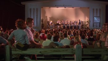 Movie still from “Body Heat” (1981), directed by Lawrence Kasdan – A crowd of people sitting in front of an audience; Wide shot, Over the shoulder angle