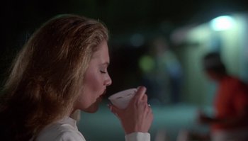Movie still from “Body Heat” (1981), directed by Lawrence Kasdan – A woman drinking from a cup in a dark room; Close Up shot, Over the shoulder angle