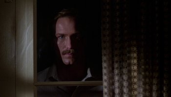 Movie still from “Body Heat” (1981), directed by Lawrence Kasdan – A man with a mustache looking out of a window; Close Up shot, Low angle