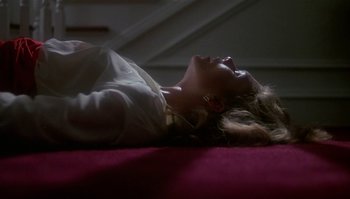 Movie still from “Body Heat” (1981), directed by Lawrence Kasdan – A woman laying on the ground with her eyes closed; Medium shot, High angle
