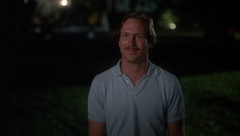 Movie still from “Body Heat” (1981), directed by Lawrence Kasdan – A man in a white shirt standing in the grass; Close Up shot, Low angle