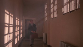 Movie still from “Body Heat” (1981), directed by Lawrence Kasdan – A man walking down a hallway holding a briefcase; Wide shot, Low angle