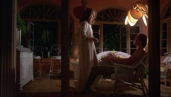 Movie still from “Body Heat” (1981), directed by Lawrence Kasdan – A woman standing in front of a table in a living room; Wide shot, Low angle