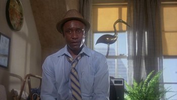 Movie still from “Body Heat” (1981), directed by Lawrence Kasdan – A man wearing a hat and a tie in front of a window; Medium shot, Low angle