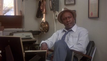 Movie still from “Body Heat” (1981), directed by Lawrence Kasdan – An older man sitting in a chair in front of an old fashioned typewriter; Medium shot, Low angle