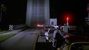Movie still from “Body Heat” (1981), directed by Lawrence Kasdan – A man sitting at a table on the side of a road; Wide shot, High angle
