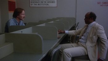 Movie still from “Body Heat” (1981), directed by Lawrence Kasdan – Two men sitting at a table in front of each other; Wide shot, Over the shoulder angle