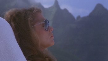 Movie still from “Body Heat” (1981), directed by Lawrence Kasdan – A woman wearing sunglasses looking at a mountain; Close Up shot, Low angle