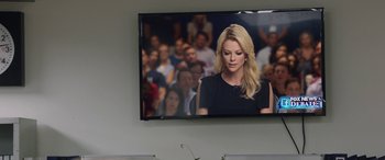 Movie still from “Bombshell” (2019), directed by Jay Roach – A television screen showing a woman in front of an audience; Medium shot, Over the shoulder angle