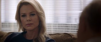 Movie still from “Bombshell” (2019), directed by Jay Roach – A woman sitting on top of a brown couch in front of a window; Close Up shot, Over the shoulder angle