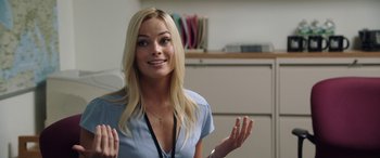 Movie still from “Bombshell” (2019), directed by Jay Roach – A beautiful blonde woman with long blonde hair wearing a blue shirt; Close Up shot, Over the shoulder angle