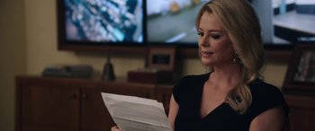 Movie still from “Bombshell” (2019), directed by Jay Roach – A woman in a black shirt is reading a piece of paper in front of a television; Close Up shot, Over the shoulder angle