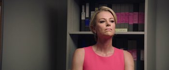 Movie still from “Bombshell” (2019), directed by Jay Roach – A woman in a pink dress is standing in front of a book shelf; Close Up shot, Over the shoulder angle