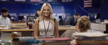 Movie still from “Bombshell” (2019), directed by Jay Roach – A beautiful blonde woman in a white dress; Medium shot, Over the shoulder angle