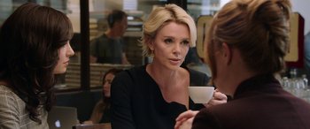 Movie still from “Bombshell” (2019), directed by Jay Roach – A woman sitting at a table with a cup of coffee; Close Up shot, Over the shoulder angle