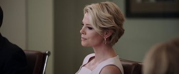 Movie still from “Bombshell” (2019), directed by Jay Roach – A woman with short blonde hair sitting in a chair looking to her left; Close Up shot, Over the shoulder angle