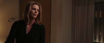 Movie still from “Bombshell” (2019), directed by Jay Roach – A woman in a black shirt is standing in a room; Close Up shot, Over the shoulder angle