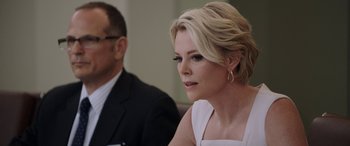 Movie still from “Bombshell” (2019), directed by Jay Roach – A woman sitting next to a man in a suit; Close Up shot, Over the shoulder angle
