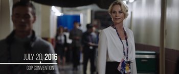 Movie still from “Bombshell” (2019), directed by Jay Roach – A woman in a white jacket and a lanyard; Medium shot, Over the shoulder angle
