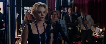 Movie still from “Bombshell” (2019), directed by Jay Roach – A group of people standing in front of a crowd; Medium shot, Over the shoulder angle