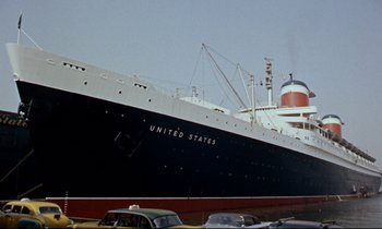 Movie still from “Bon Voyage!” (1962), directed by James Neilson – A black and white ship and some cars parked in a parking lot; Extreme Wide shot, Low angle