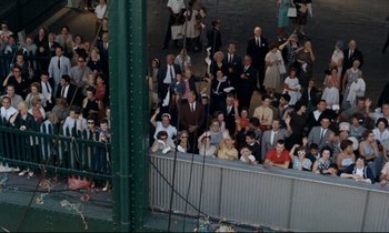 Movie still from “Bon Voyage!” (1962), directed by James Neilson – A group of people standing on top of a green fence; Extreme Wide shot, Overhead angle
