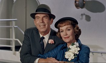 Movie still from “Bon Voyage!” (1962), directed by James Neilson – An older man and a younger woman posing for a picture; Medium shot, High angle