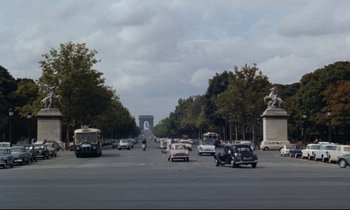 Movie still from “Bon Voyage!” (1962), directed by James Neilson – Cars and buses driving down a street near a monument; Extreme Wide shot, High angle