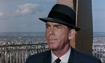 Movie still from “Bon Voyage!” (1962), directed by James Neilson – A person wearing a suit and a hat; Close Up shot, Over the shoulder angle