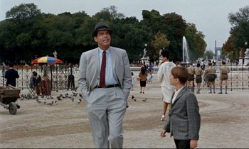 Movie still from “Bon Voyage!” (1962), directed by James Neilson – An older man and a young boy walking through a park; Wide shot, Over the shoulder angle