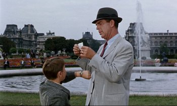 Movie still from “Bon Voyage!” (1962), directed by James Neilson – An older man and a young boy in a park; Medium shot, Over the shoulder angle