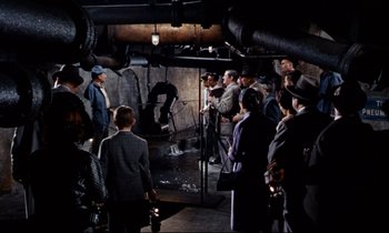 Movie still from “Bon Voyage!” (1962), directed by James Neilson – A group of people standing around in a room; Wide shot, High angle