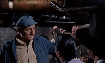 Movie still from “Bon Voyage!” (1962), directed by James Neilson – An older man in a blue hat is talking to a woman in a blue dress; Medium shot, Low angle