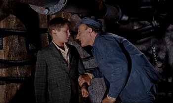 Movie still from “Bon Voyage!” (1962), directed by James Neilson – A man and a young boy talking in a room; Medium shot, High angle