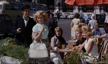 Movie still from “Bon Voyage!” (1962), directed by James Neilson – A group of people sitting at a table outside; Wide shot, High angle