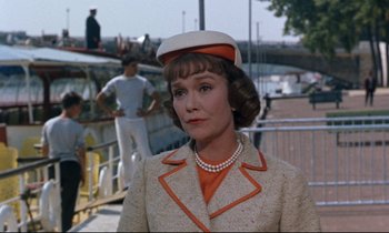 Movie still from “Bon Voyage!” (1962), directed by James Neilson – A woman wearing a white hat and a jacket; Medium shot, Over the shoulder angle