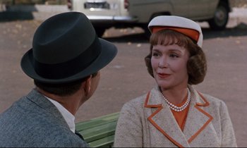 Movie still from “Bon Voyage!” (1962), directed by James Neilson – An older woman wearing a hat talking to an older man wearing a hat; Medium shot, Over the shoulder angle