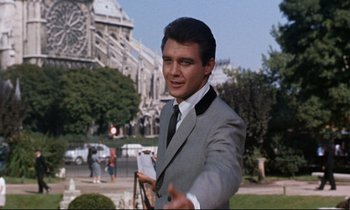 Movie still from “Bon Voyage!” (1962), directed by James Neilson – A man wearing a suit and tie standing in front of a building; Medium shot, Low angle