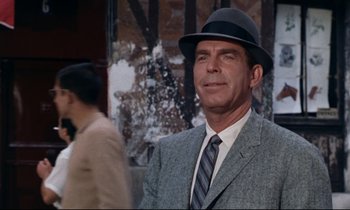 Movie still from “Bon Voyage!” (1962), directed by James Neilson – A man wearing a hat and a suit and tie; Close Up shot, Over the shoulder angle