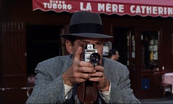 Movie still from “Bon Voyage!” (1962), directed by James Neilson – A man taking a picture with a camera; Close Up shot, Low angle