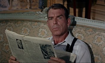 Movie still from “Bon Voyage!” (1962), directed by James Neilson – A man sitting in a chair reading a newspaper; Close Up shot, Over the shoulder angle