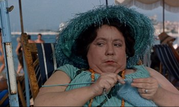 Movie still from “Bon Voyage!” (1962), directed by James Neilson – An older woman is knitting on the beach; Close Up shot, High angle