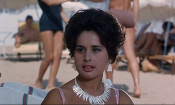 Movie still from “Bon Voyage!” (1962), directed by James Neilson – A woman wearing a white necklace and a pink dress; Close Up shot, High angle